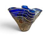 un vase en verre bleu posé sur une surface blanche