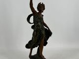 une statue en bronze représentant une femme tenant un oiseau dans la main