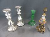 trois bougeoirs en argent et deux bougeoirs en verre vert posés sur une table