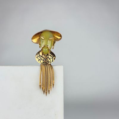 a close up of a gold ring with a green face on it