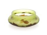 un bol en verre vert orné d'un motif de feuilles jaunes