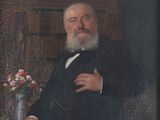 portrait of a man in a suit and tie sitting in a chair with a vase of flowers in front of him