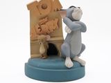 a figurine of a cat and mouse in front of a sign