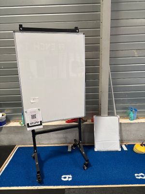un tableau blanc posé sur un tapis bleu devant un tableau blanc