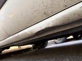a cat that is sitting under a car on the street