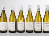 six bouteilles de vin blanc sont alignées
