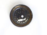 a black and gold plate with a white dot on it
