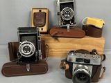 trois vieux appareils photo posés sur une caisse en bois