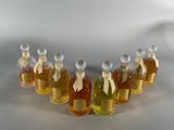 six bottles of honey syrup lined up in a row on a white surface
