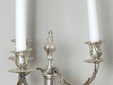 two white candles that are on a silver candle holder