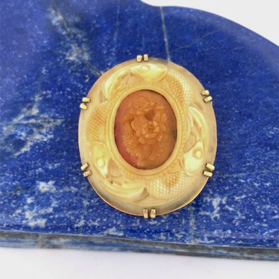 une image représentant une broche en or posée sur une pierre bleue