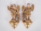 deux statues dorées représentant des anges, posées sur un fond blanc