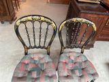 pair of antique painted wooden chairs with colorful cushions on them