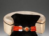 an orange beaded bracelet with a gold clasp on a black velvet bag