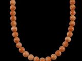 an orange jade bead necklace on a black background