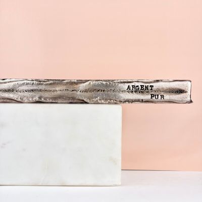 a close up of a knife on a marble block with a pink background