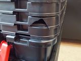 a stack of black plastic containers with red handles