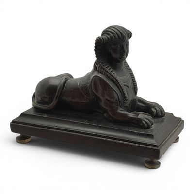 statue d'un lion posée sur un socle en bois, sur fond blanc