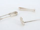 three silver spoons and a spoon rest on a white surface