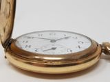 a gold pocket watch sitting on a white surface