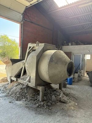 une bétonnière dans un bâtiment où se trouve un tas de gravats