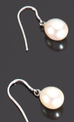 une paire de boucles d'oreilles en perles blanches posées sur un fond noir