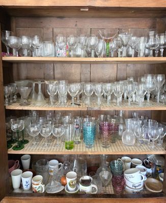 de nombreuses tasses et verres sur les étagères de ce buffet