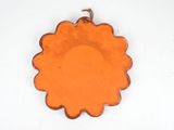 an orange glass plate with a flower design hanging from it ' s side