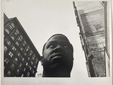 photographie en noir et blanc d'un homme debout devant un grand immeuble
