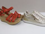 two pairs of silver and red shoes on a white surface