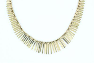 gros plan d'un collier en or sur fond blanc