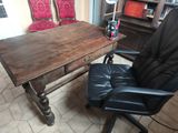 a desk with a chair and a bookcase in the background