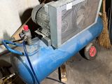 a blue air compressor sitting in a garage next to a pile of boxes