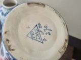 a person holding a blue and white vase with a triangle on it