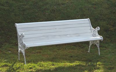 un banc blanc posé au milieu d'un champ herbeux