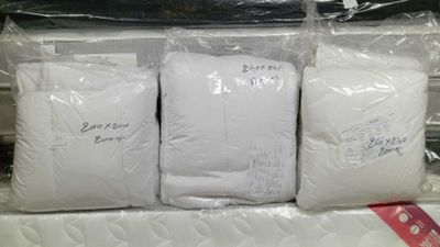 three bags of white pillows on top of each other