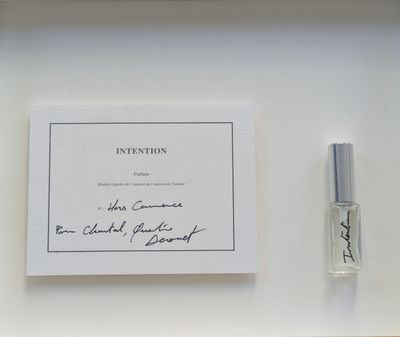 un flacon de parfum posé à côté d'une carte sur une étagère