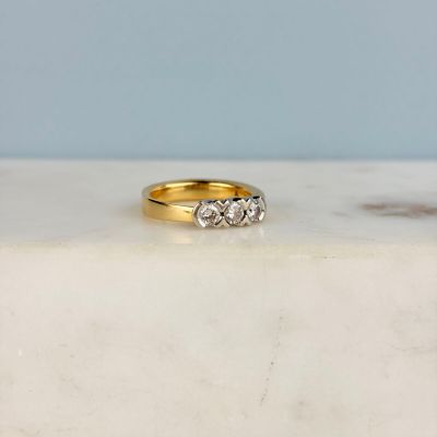 une photo d'une bague en diamant à trois pierres posée sur une dalle de marbre