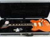 an orange electric guitar sitting in a case on a white surface