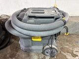 a vacuum that is sitting on the ground with a hose attached to it