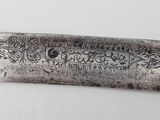 a silver knife with a design on it sitting on a table