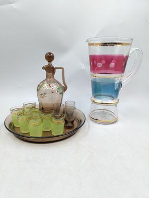 two cups and a jug on a tray with a tray of shot glasses