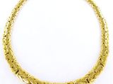 un collier plaqué or présentant un motif complexe sur fond blanc