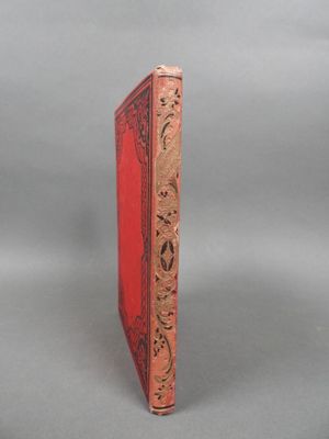 an old red book sitting on top of a gray surface