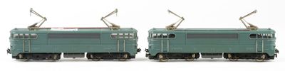 two toy trains sitting side by side on a white surface