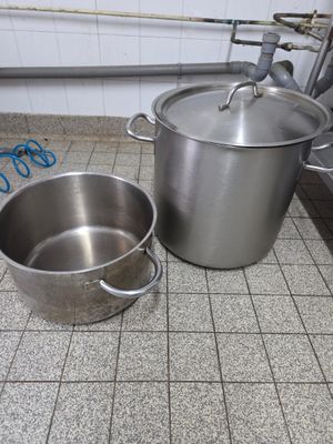 des casseroles et des poêles posées sur le carrelage d'une cuisine