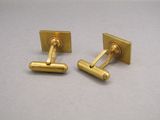 pair of gold plated cufflinks on a grey surface
