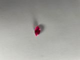 a close up of a red heart shaped diamond on a white surface