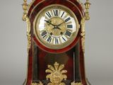 a red and gold clock with a bird on it