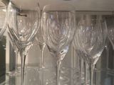 many wine glasses sitting on a glass shelf in the kitchen